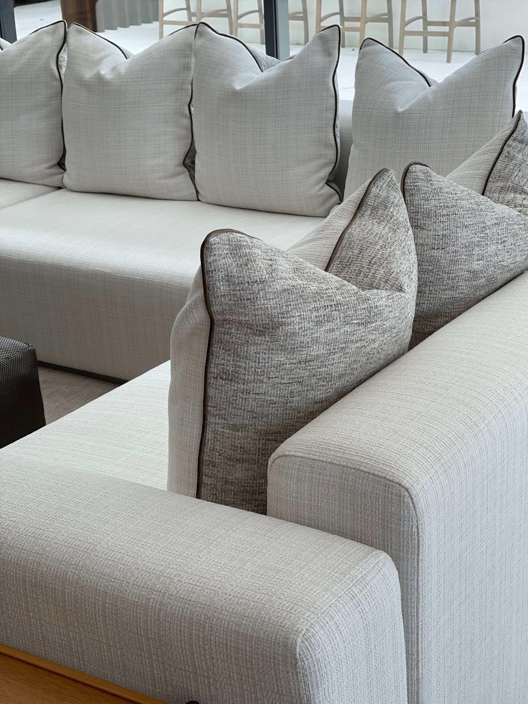 A white upholstered sectional layered with cream and grey linen pillows.