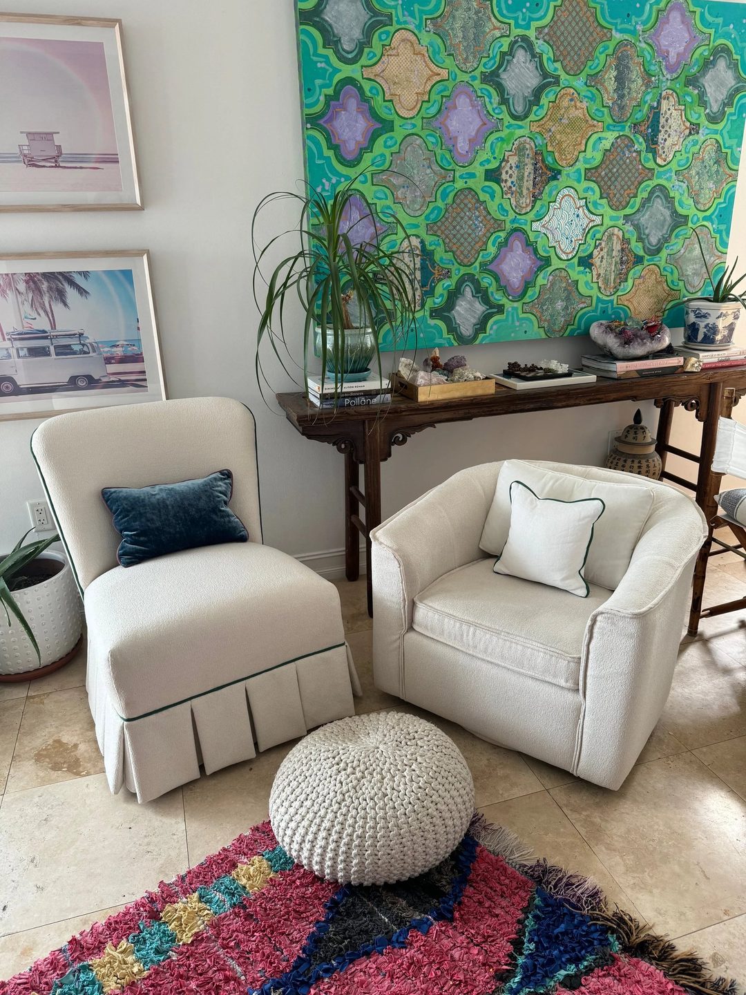 A skirted slipper chair and a swivel club chair in cream fabric with green piping, beside a knit pouf on a colourful rug.