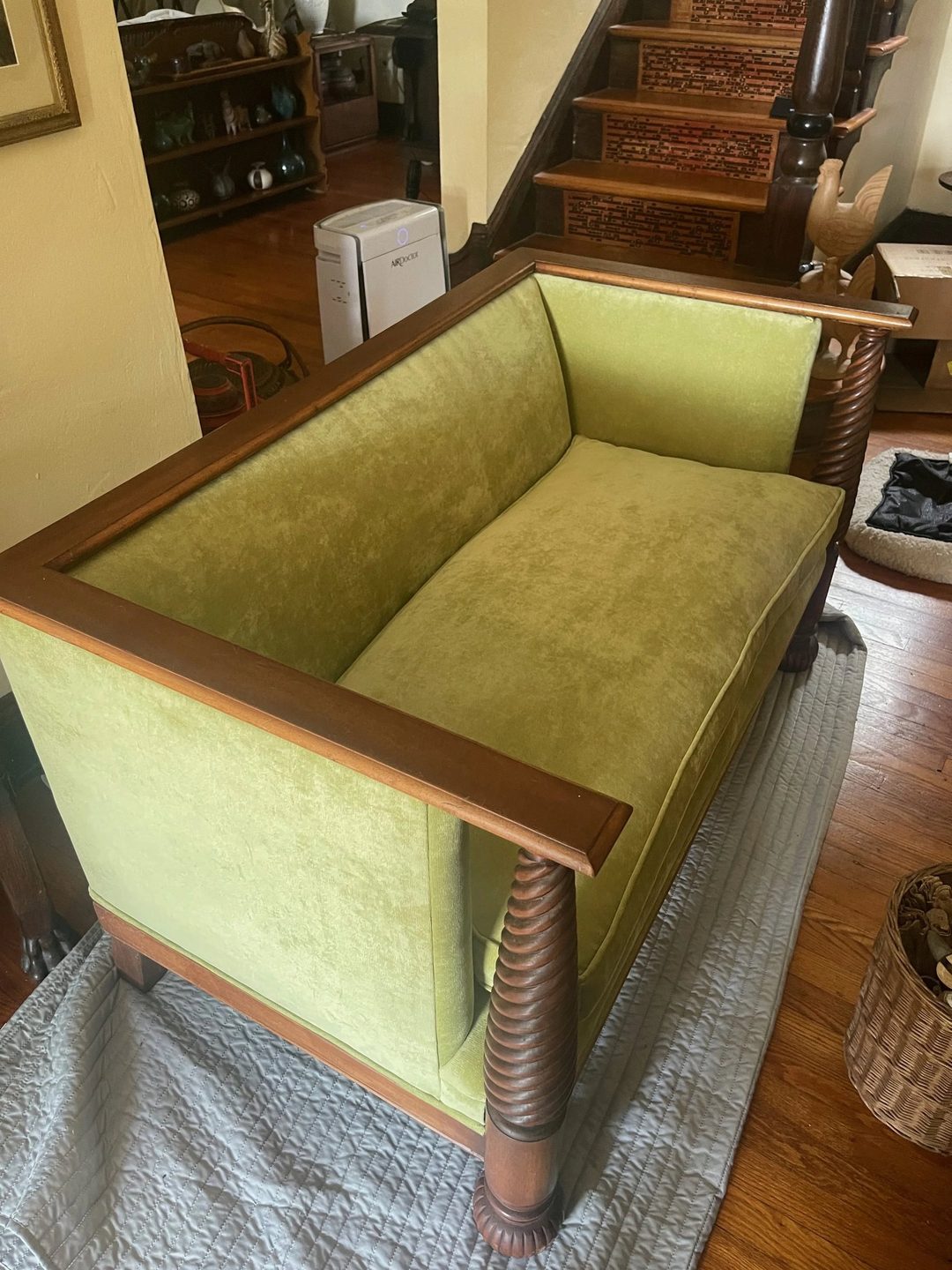A wood-framed settee with spiral-turned legs, upholstered in green velvet.