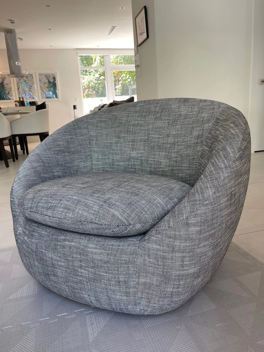 A rounded barrel chair with a loose seat cushion, upholstered in black-and-white tweed.