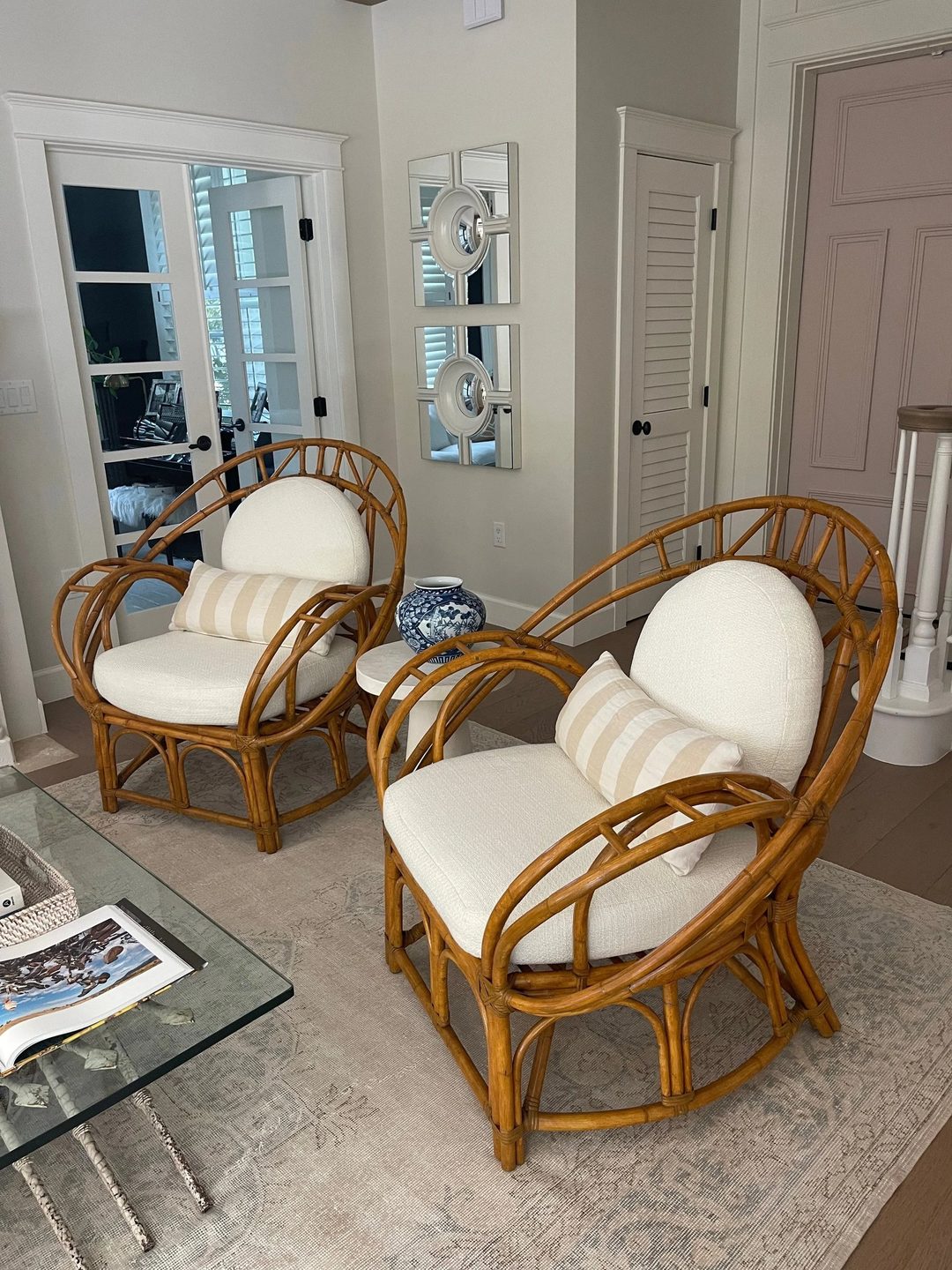 Two bentwood rattan lounge chairs with cream seat and back cushions and striped lumbar pillows.