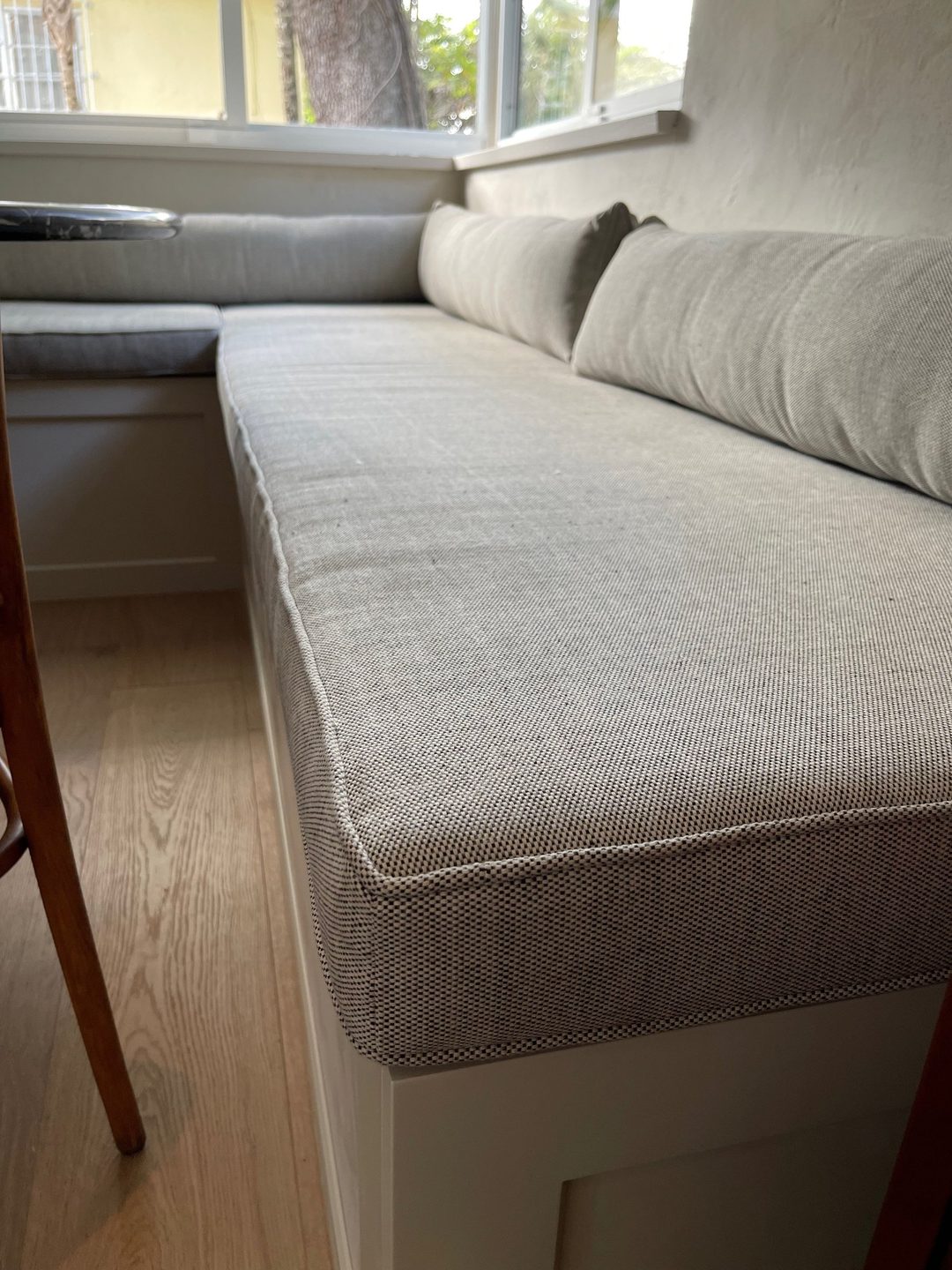 Close-up of a built-in window seat cushion in a grey and cream weave, with self piping and bolsters.